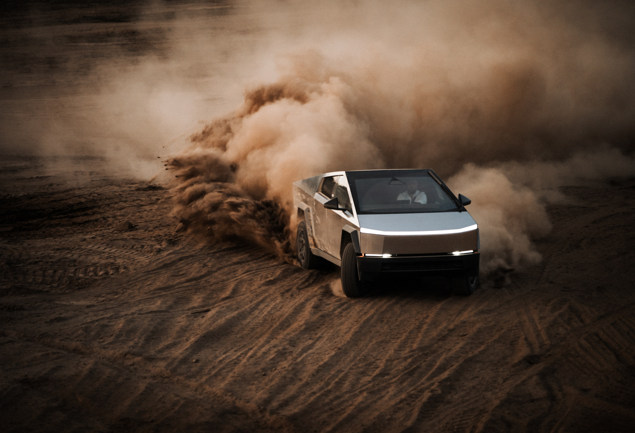 Tesla Cybertruck drifting through dust at dusk