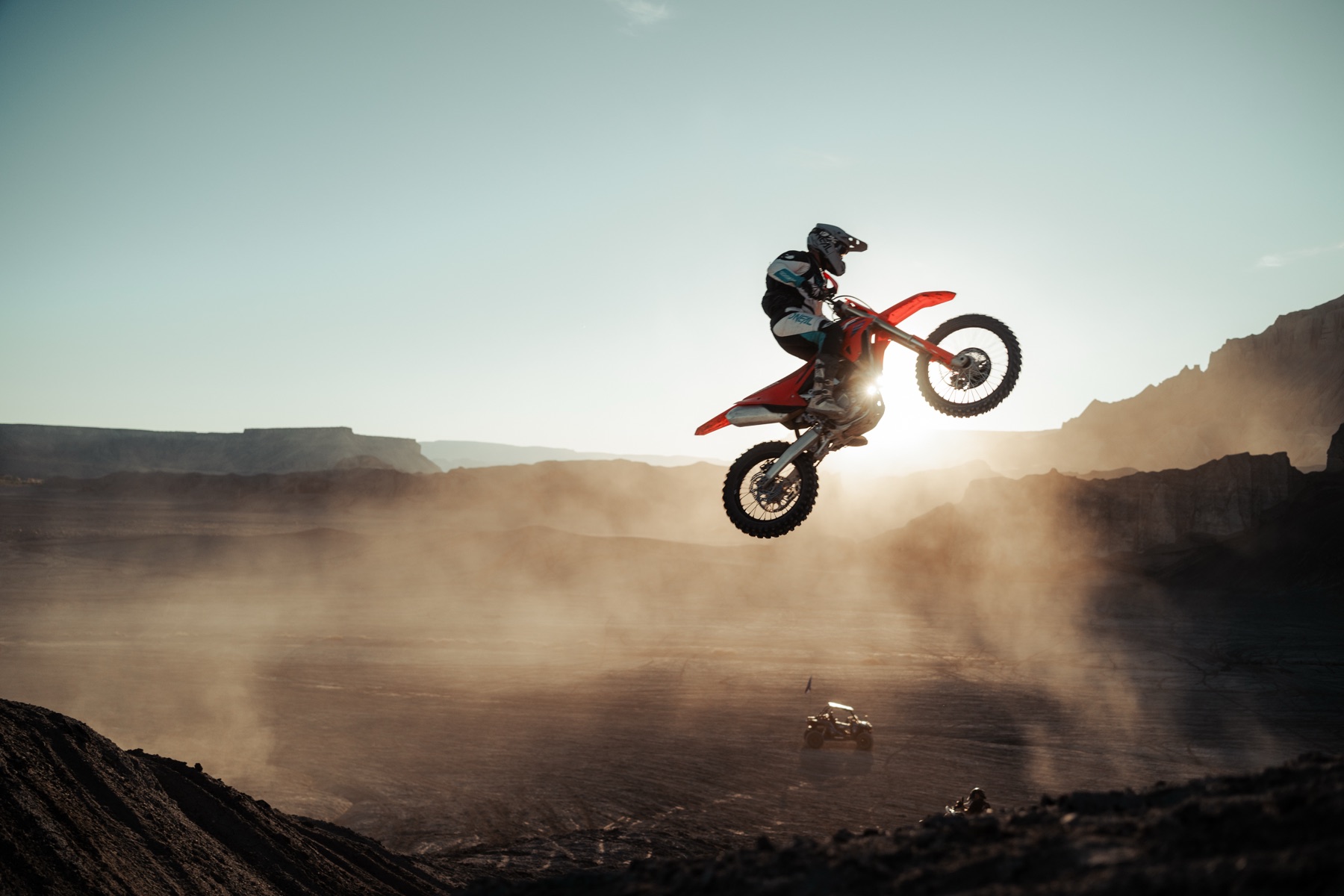 Dirt bike mid-air kicking up dust against a desert mesa, Dust to Dust